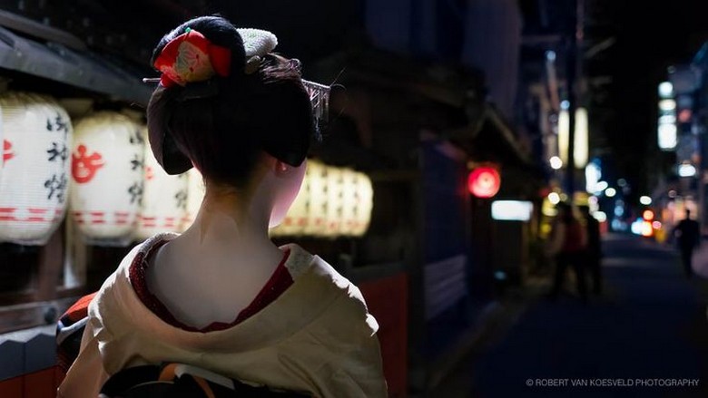 Một maiko mặc kimono đi nhanh trên phố Hanamikoji lúc lên đèn