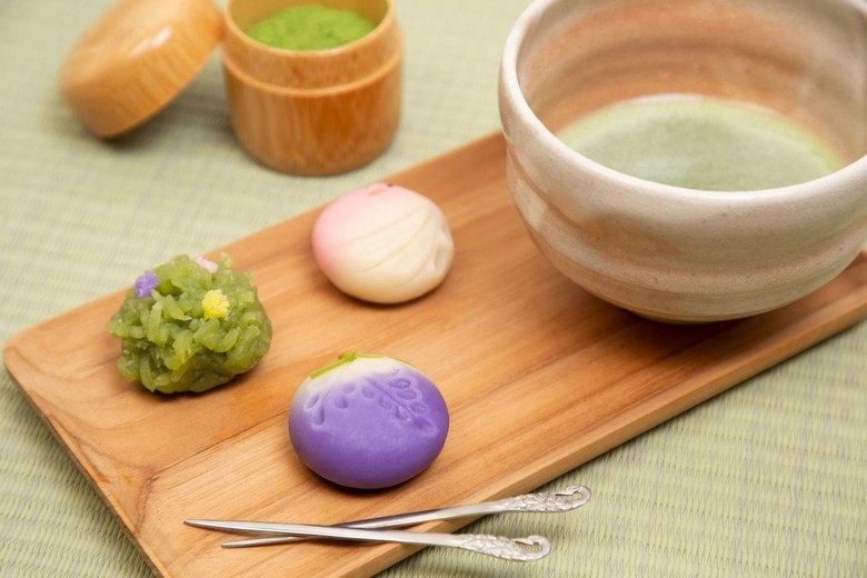 Một đĩa wagashi nhiều màu bày cạnh chén trà xanh