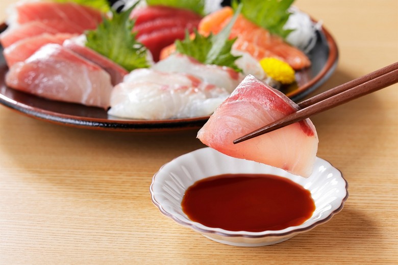 Cách cầm miếng sushi chấm nhẹ phía cá vào đĩa xì dầu