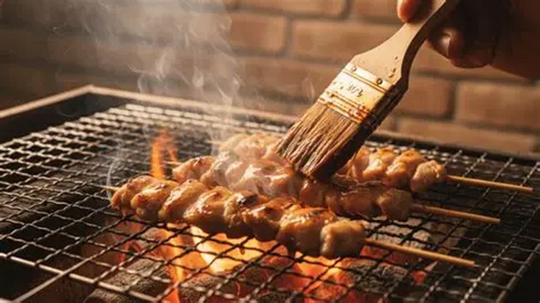 Xiên yakitori đang nướng trên than hồng, khói bay nhẹ, ánh lửa vàng