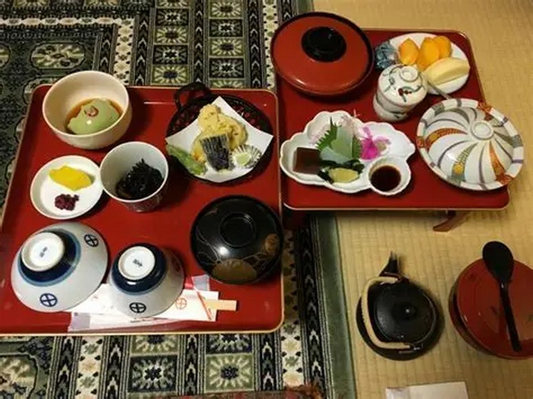 Bữa ăn kaiseki truyền thống phục vụ tại ryokan — nhiều món nhỏ bày trên khay gỗ sơn mài