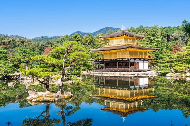 Chùa Vàng Kinkakuji nhìn từ góc cầu gỗ bên bờ hồ, có du khách đứng thưởng ngoạn