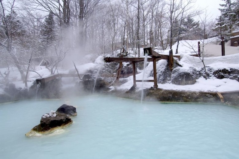 Khu rotenburo (onsen ngoài trời) với cảnh núi tuyết mùa đông tại Hokkaido hoặc Nagano