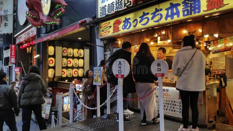 Hàng takoyaki đường phố Osaka với người đứng xếp hàng chờ mua